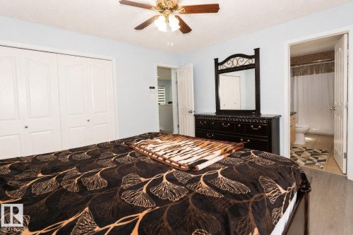 Light blue walls with a ceiling fan featuring wood-finish blades - 8523 7 Avenue Sw, Edmonton, AB 