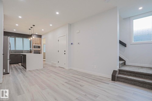 Open-concept living space featuring wood-finish flooring, recessed lighting, and a modern kitchen - 10628 81 Street Nw, Edmonton, AB 