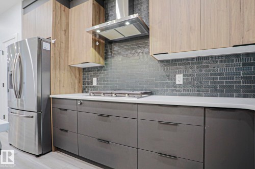 Contemporary kitchen featuring a stainless steel refrigerator, white countertops, and a decorative tile backsplash - 10628 81 Street Nw, Edmonton, AB 