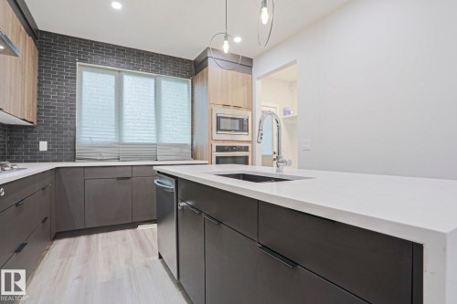 Modern kitchen featuring a central island with an undermount sink and chrome gooseneck faucet - 10628 81 Street Nw, Edmonton, AB 