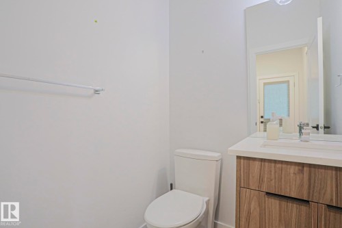 Contemporary vanity with wood-finish cabinetry, integrated sink, and light-toned countertop - 10628 81 Street Nw, Edmonton, AB 