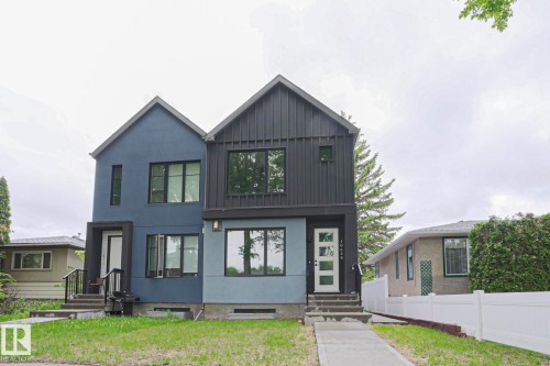 Contemporary duplex featuring a striking two-tone facade with dark gray vertical siding and blue stucco - 10628 81 Street Nw, Edmonton, AB 
