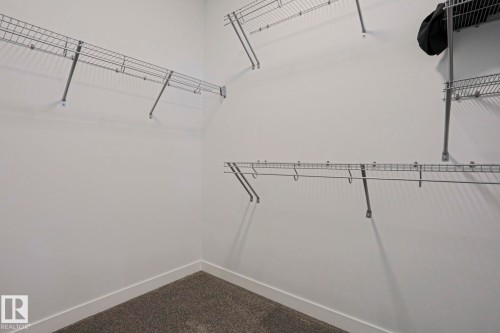 Walk-in closet featuring wire shelving, hanging rods, and carpeting - 10628 81 Street Nw, Edmonton, AB 