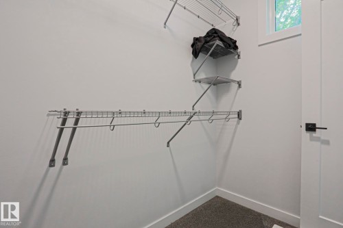 Customizable wire shelving system, corner shelving, hanging rod, neutral wall color, and dark carpet flooring - 10628 81 Street Nw, Edmonton, AB 
