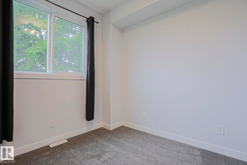 Interior room featuring white walls, gray carpet, white baseboards, and a white framed window - 10628 81 Street Nw, Edmonton, AB 