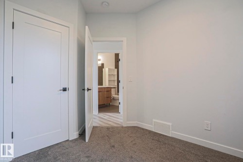 Neutral-toned room featuring a soft gray carpet, white baseboards, and light gray walls - 10628 81 Street Nw, Edmonton, AB 