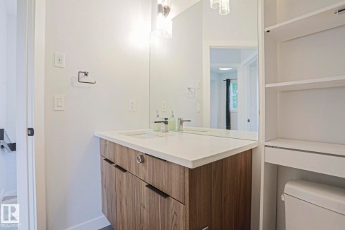 Modern bathroom vanity featuring wood-finish cabinetry, a white countertop, and a rectangular undermount sink - 10628 81 Street Nw, Edmonton, AB 