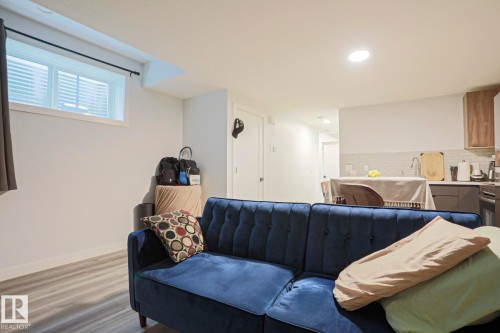 Open-concept living area with wood-finish flooring, a window featuring horizontal blinds, and recessed lighting - 10628 81 Street Nw, Edmonton, AB 
