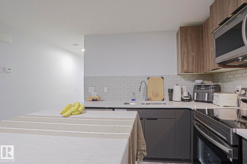 Contemporary kitchen featuring dark gray lower cabinetry and wood-look upper cabinets - 10628 81 Street Nw, Edmonton, AB 