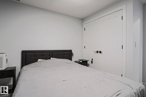 Bedroom featuring a tufted upholstered headboard, a built-in closet with double doors, and black hardware - 10628 81 Street Nw, Edmonton, AB 