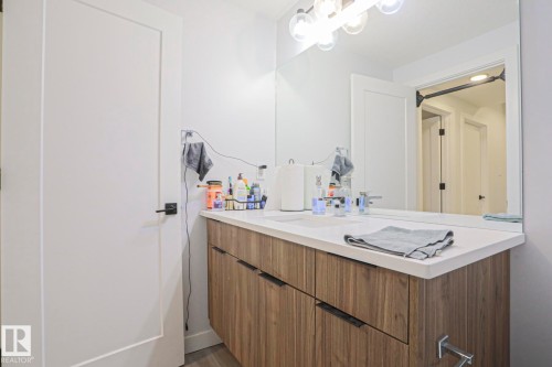 Bathroom featuring a dual-sink vanity with a light wood-finish cabinet, white countertop, and modern chrome fixtures - 10628 81 Street Nw, Edmonton, AB 