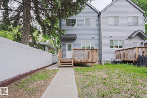 Rear exterior featuring a wood-decked patio with stairs, light blue vinyl siding, and white-framed windows - 10628 81 Street Nw, Edmonton, AB 