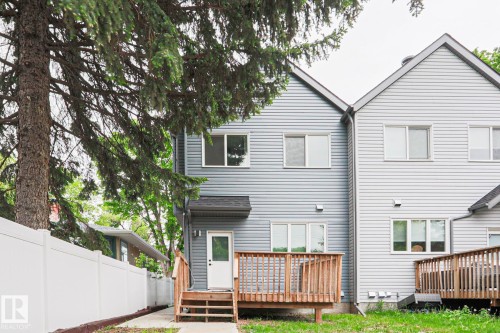 Rear exterior featuring light grey siding and a wooden deck with railing - 10628 81 Street Nw, Edmonton, AB 