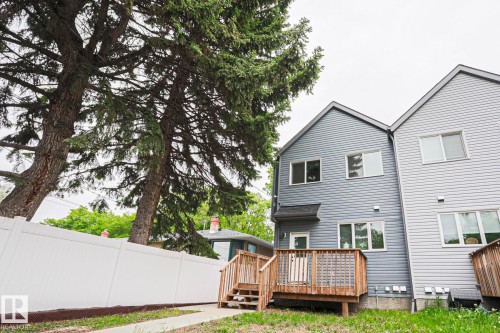 Rear exterior featuring horizontal siding, a private wooden deck, and a white privacy fence - 10628 81 Street Nw, Edmonton, AB 
