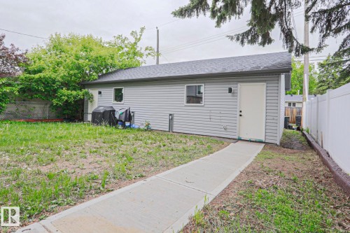 Detached garage with horizontal siding, a dark shingle roof, and multiple windows - 10628 81 Street Nw, Edmonton, AB 