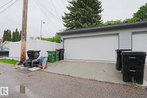 Rear-entry garage with two white garage doors, grey siding, and a concrete driveway - 10628 81 Street Nw, Edmonton, AB 