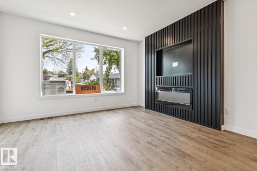 Expansive window, recessed lighting, wood-finish flooring, built-in entertainment center, and electric fireplace - 11336 130 Street Nw, Edmonton, AB 