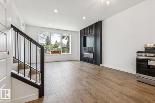 Open-concept living area with wood-finish flooring, recessed lighting, and large windows - 11336 130 Street Nw, Edmonton, AB 