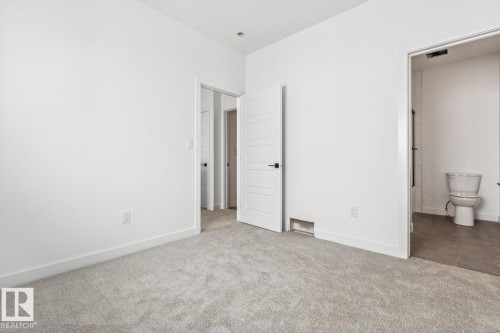Plush grey carpeting, white interior doors with horizontal panels, and a white toilet with a tile floor - 11336 130 Street Nw, Edmonton, AB 
