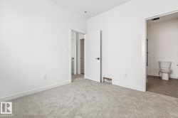 Plush grey carpeting, white interior doors with horizontal panels, and a white toilet with a tile floor - 