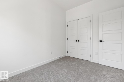 Neutral wall paint, plush carpeting, white trim, modern interior doors, and matte black hardware - 11336 130 Street Nw, Edmonton, AB 