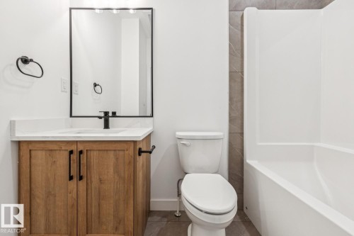 Wood-finish vanity with white countertop, undermount sink, and matte black faucet - 11336 130 Street Nw, Edmonton, AB 