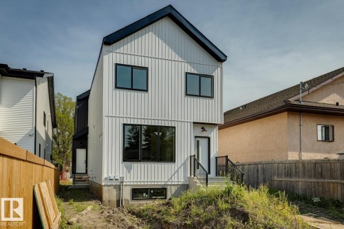 Modern exterior with white vertical panel siding, black-framed windows, and a black gable roof - 11336 130 Street Nw, Edmonton, AB 