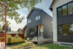 Modern exterior featuring dark corrugated siding, multiple windows, and a light wood-finish accent panel at the entrance - 