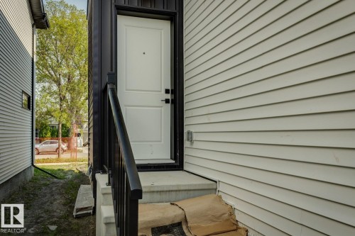 White paneled entry door with black hardware, black railing, and concrete steps - 11336 130 Street Nw, Edmonton, AB 
