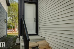 White paneled entry door with black hardware, black railing, and concrete steps - 