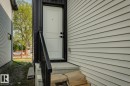 White paneled entry door with black hardware, black railing, and concrete steps - 11336 130 Street Nw, Edmonton, AB 