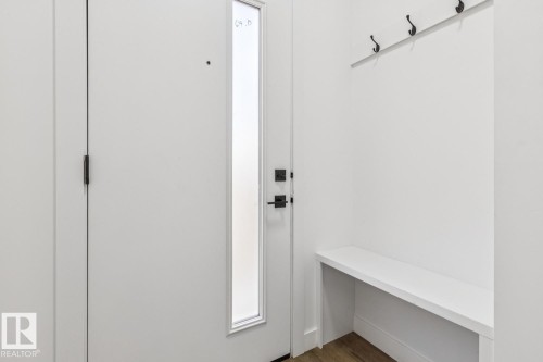 Entryway featuring a built-in bench, wall-mounted coat rack, and wood-finish flooring - 11336 130 Street Nw, Edmonton, AB 