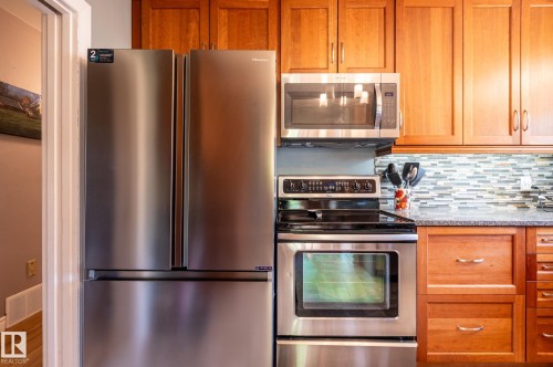 Kitchen featuring stainless steel appliances, including a French door refrigerator, electric range, and built-in microwave - 14708 108 Av, Edmonton, AB 
