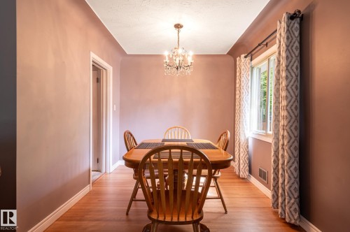 Formal dining area featuring wood-finish flooring and a crystal chandelier - 14708 108 Av, Edmonton, AB 