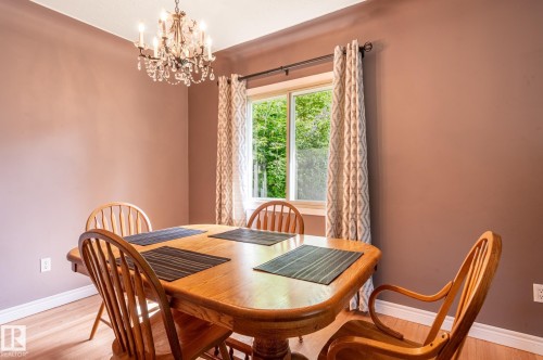 Dining area featuring wood-finish flooring, a crystal chandelier, and a window with natural light - 14708 108 Av, Edmonton, AB 