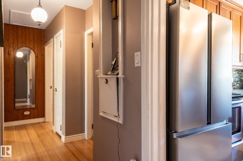 Hallway featuring wood-finish flooring and a wood panel accent wall - 14708 108 Av, Edmonton, AB 