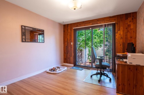 Sliding glass doors opening to outdoor space, complemented by a wood-paneled accent wall - 14708 108 Av, Edmonton, AB 