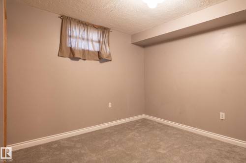 Room featuring neutral wall paint, gray carpeting, a window with curtains, white baseboards, and a ceiling light fixture - 14708 108 Av, Edmonton, AB 