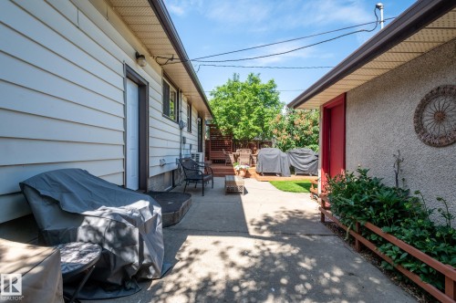 Concrete patio space offering exterior building access, a raised deck, and a planted garden bed - 14708 108 Av, Edmonton, AB 