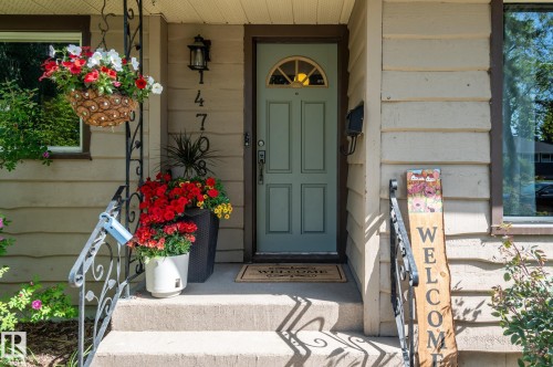 Front entry featuring a light blue paneled door with an arched glass insert, horizontal siding, concrete steps, and wrought iron handrails - 14708 108 Av, Edmonton, AB 