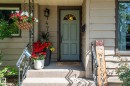 Front entry featuring a light blue paneled door with an arched glass insert, horizontal siding, concrete steps, and wrought iron handrails - 14708 108 Av, Edmonton, AB 