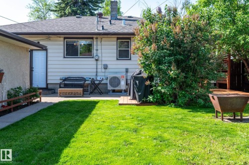 Expansive backyard featuring a lush lawn, concrete patio, and mature landscaping - 14708 108 Av, Edmonton, AB 