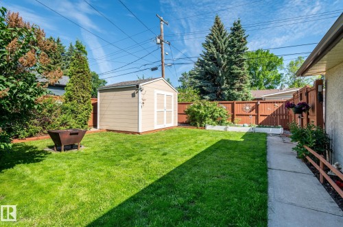 Spacious backyard featuring a manicured lawn, a detached storage shed, and a privacy fence - 14708 108 Av, Edmonton, AB 