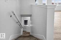Multi-level residential interior featuring a staircase with carpeted treads and a painted wood handrail with matte black brackets - 