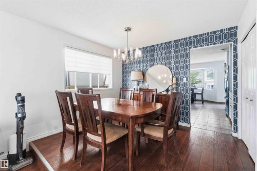 Dining area featuring wood-finish flooring and a contemporary chandelier - 18808 72A Avenue, Edmonton, AB 