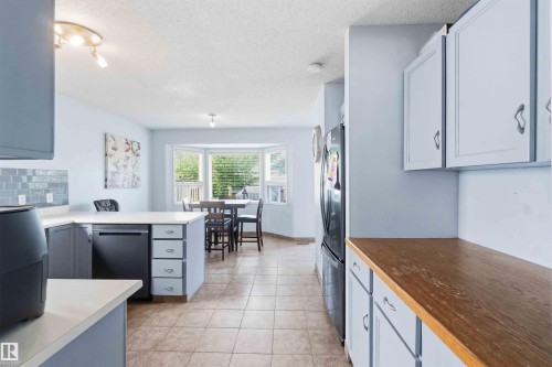 Kitchen featuring light blue cabinetry, a built-in dishwasher, and a contrasting wood-finish countertop - 18808 72A Avenue, Edmonton, AB 