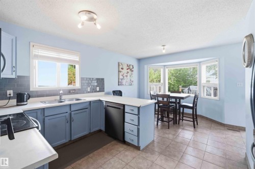 Open-concept kitchen featuring pale blue cabinetry and a light-toned countertop - 18808 72A Avenue, Edmonton, AB 