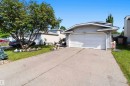 Front exterior featuring light gray siding, an attached two-car garage with a white door, a paved driveway, and a manicured lawn - 18808 72A Avenue, Edmonton, AB 