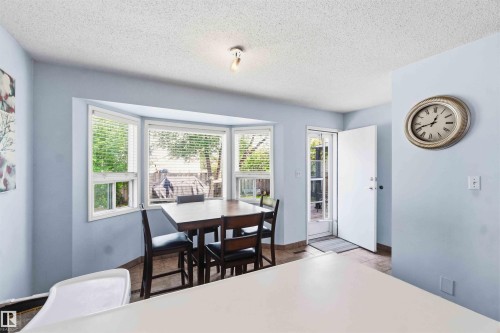Dining area featuring a bay window, ceiling-mounted track lighting, exterior access door, and tile flooring - 18808 72A Avenue, Edmonton, AB 