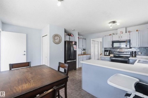 Kitchen featuring light gray cabinetry, a subway tile backsplash, white countertops, and black appliances - 18808 72A Avenue, Edmonton, AB 